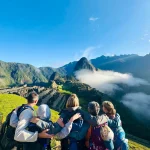 Viajeros contemplando Machu Picchu al amanecer en un tour grupal